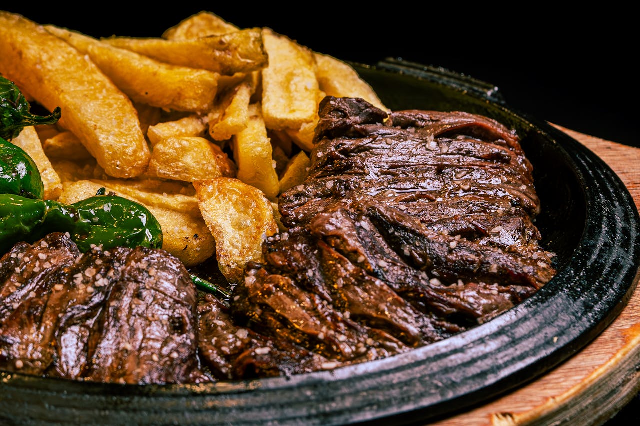 Juicy grilled steak paired with crispy fries and green peppers on a rustic plate.